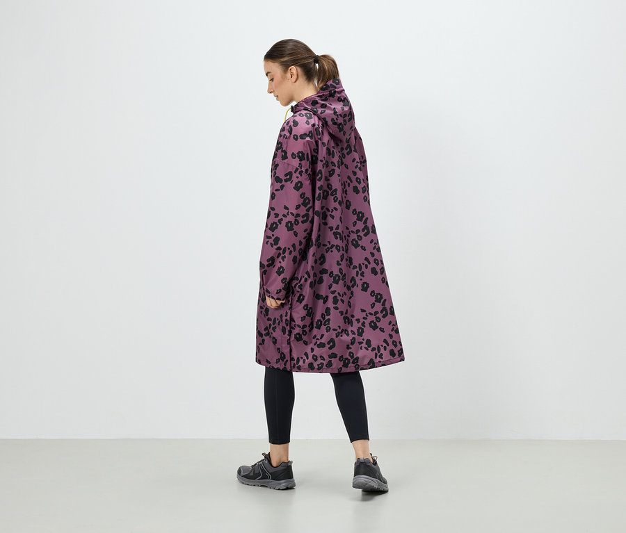 Eine Frau trägt einen lila Mantel mit schwarzem Animal-Print, schwarze Leggings und graue Turnschuhe.