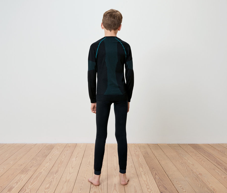 Ein Junge steht mit dem Rücken zur Kamera und trägt schwarze Thermo-Unterwäsche mit langen Ärmeln und Leggings mit türkisfarbenen Details.