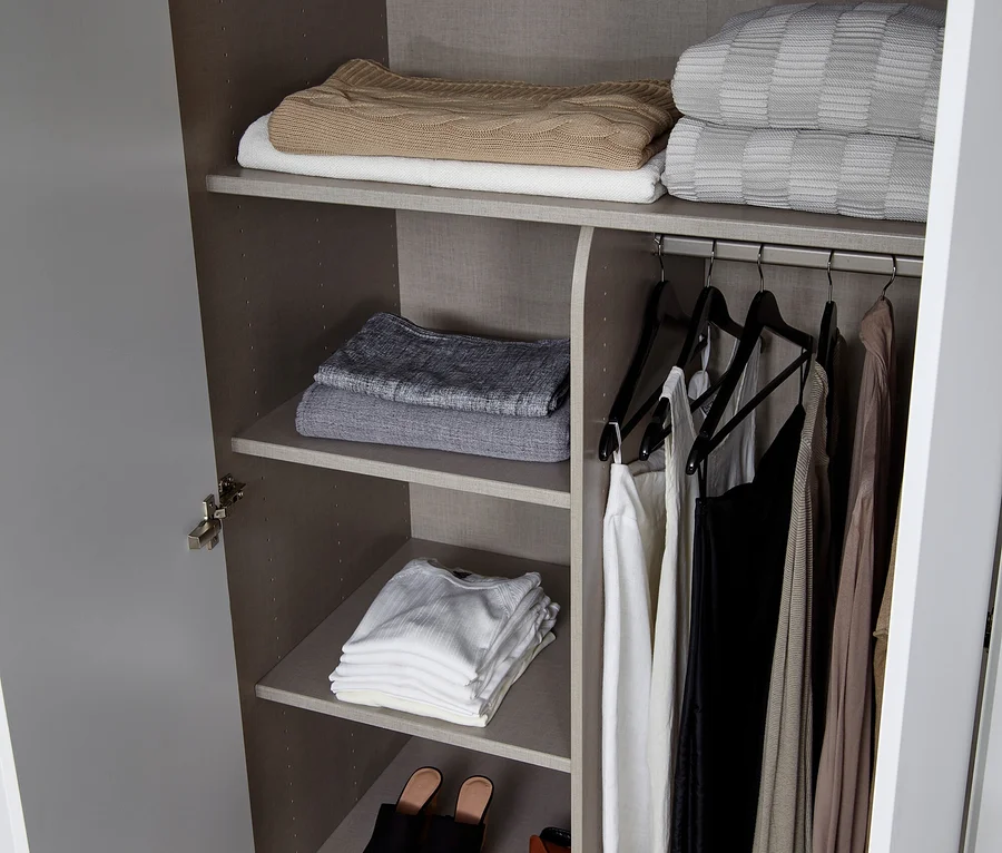 Offener Schrank mit Hut, Kleidung und Schuhen in den Regalen.