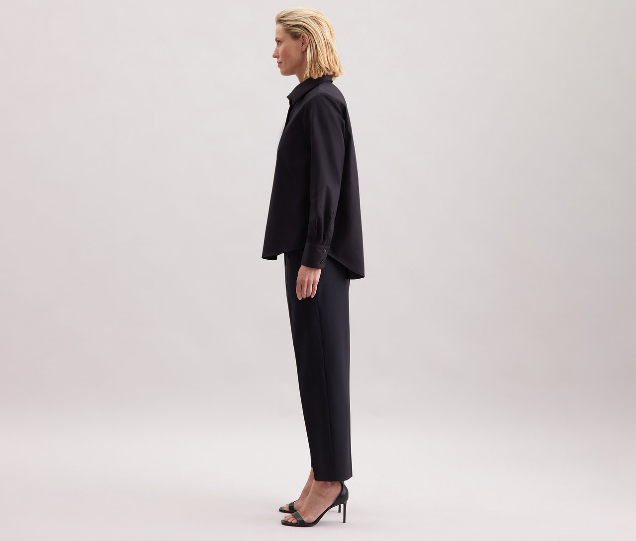 Frau trägt eine schwarze Seidensticker Regular-Bluse, schwarze Hose und hochhackige Schuhe.