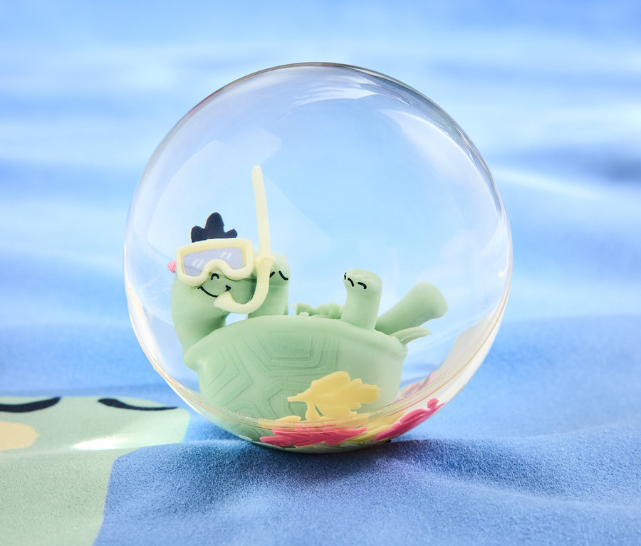 Eine grüne Schildkröte mit Taucherbrille und Schnorchel in einer durchsichtigen Kugel auf blauem Hintergrund. Produkt: XXL-Flummi