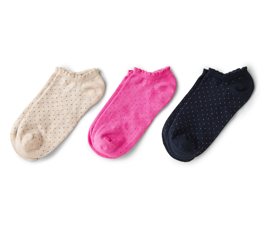 Drei Paar niedrige Socken, beige mit schwarzen Punkten, pink und marineblau mit weißen Punkten, liegen auf einem weißen Hintergrund.