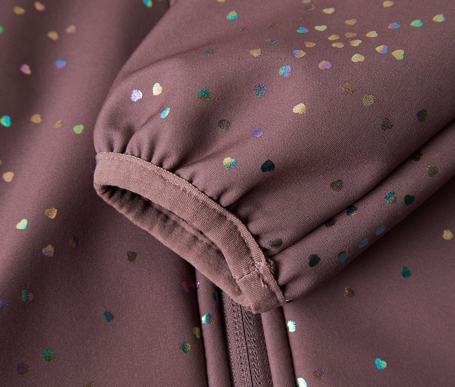 Nahaufnahme eines Ärmels und Reißverschlusses einer softshell Jacke in Lila mit bunten Herzchen.