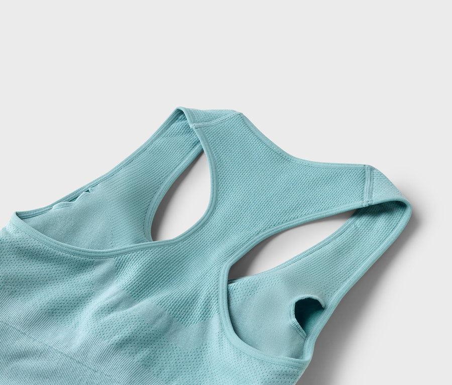 Nahaufnahme eines helltürkisfarbenen Sport-BHs mit Racerback-Design vor einem weißen Hintergrund.