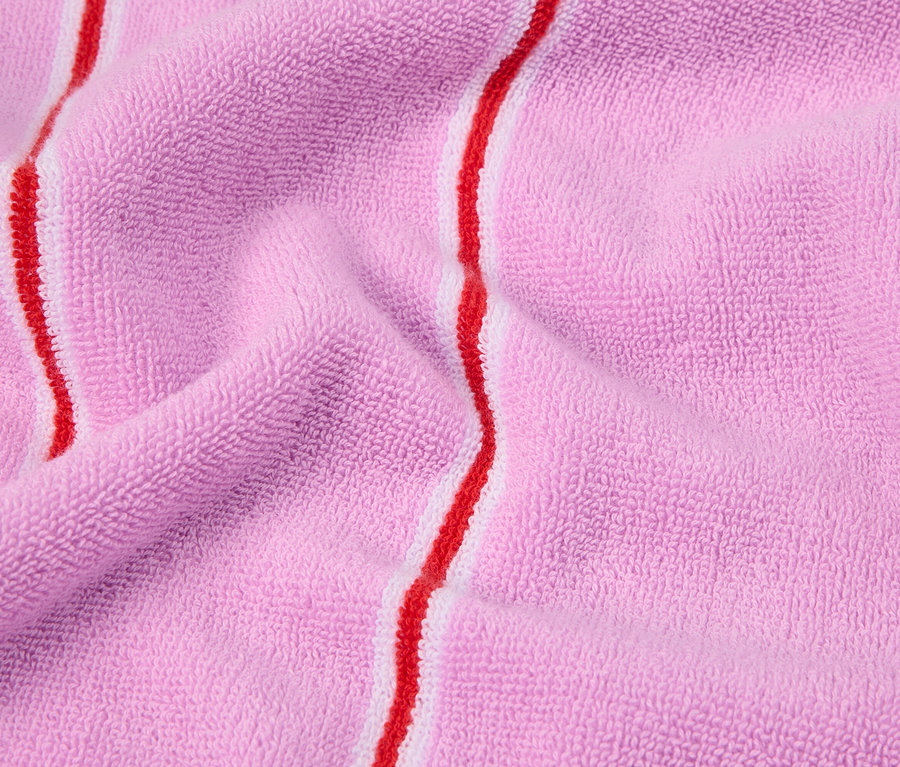 Nahaufnahme eines gefalteten, rosafarbenen Frotteehandtuchs mit roten und weißen Streifen.
