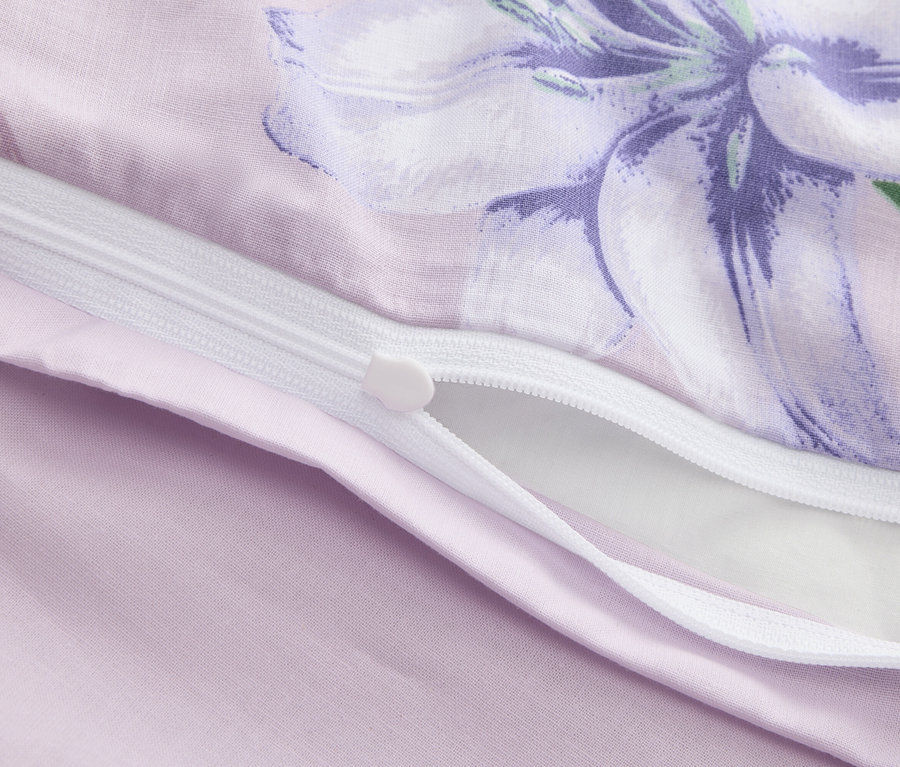 Nahaufnahme eines teilweise geöffneten lila Bettbezugs mit Blumendruck und Reißverschluss.