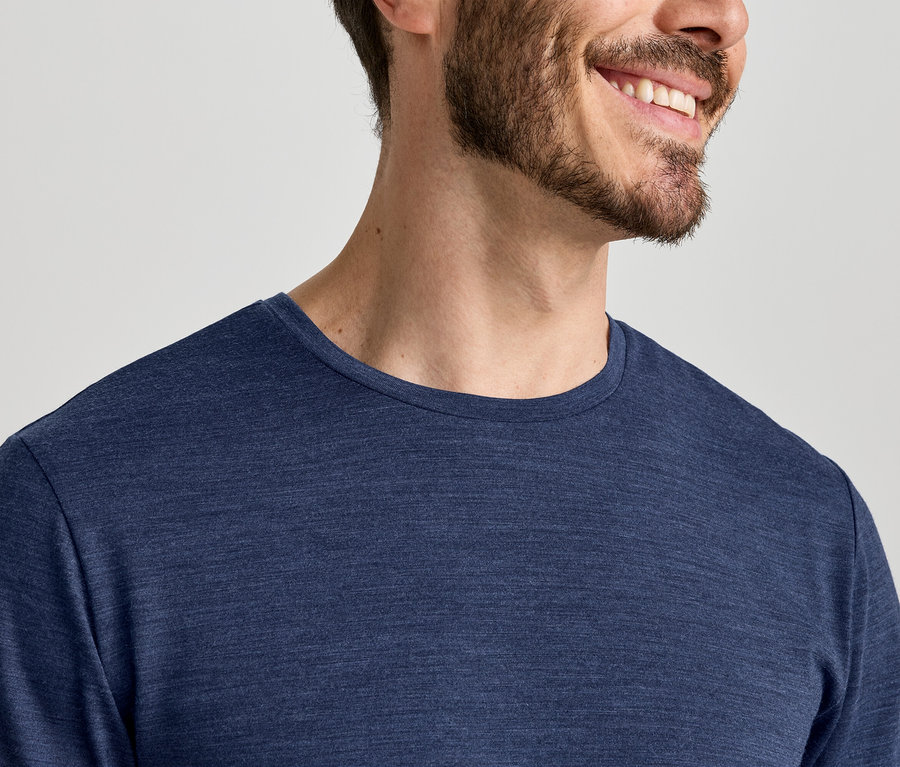 Nahaufnahme eines lächelnden Mannes mit Bart, der ein blaues Langarmshirt trägt.