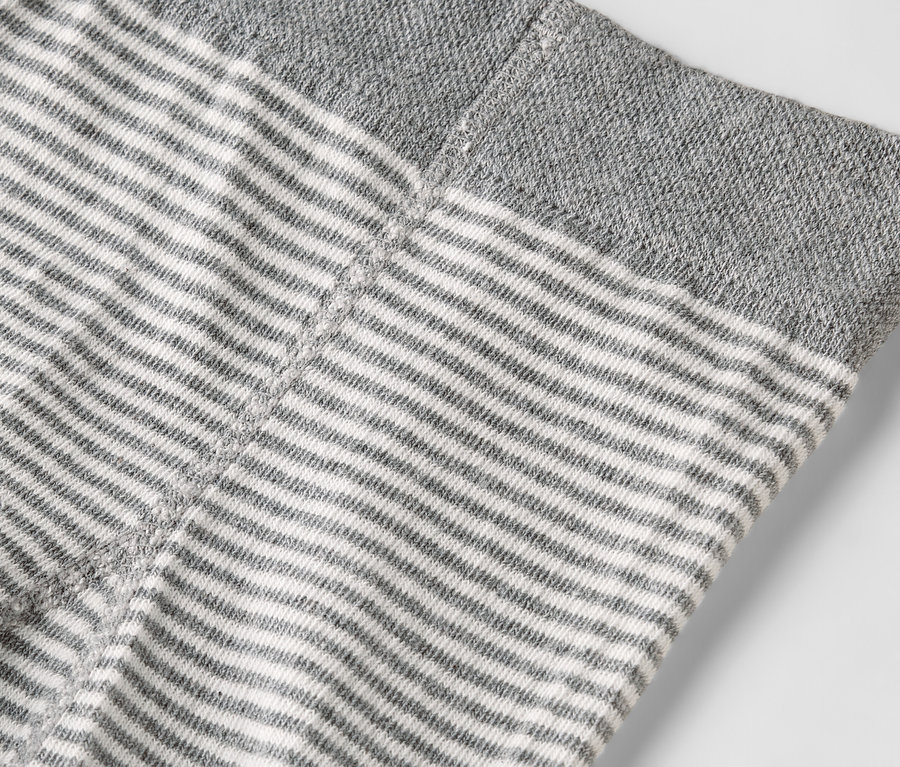Nahaufnahme eines Kleidungsstücks mit horizontalen grauen und weißen Streifen und einem grauen Saum.
