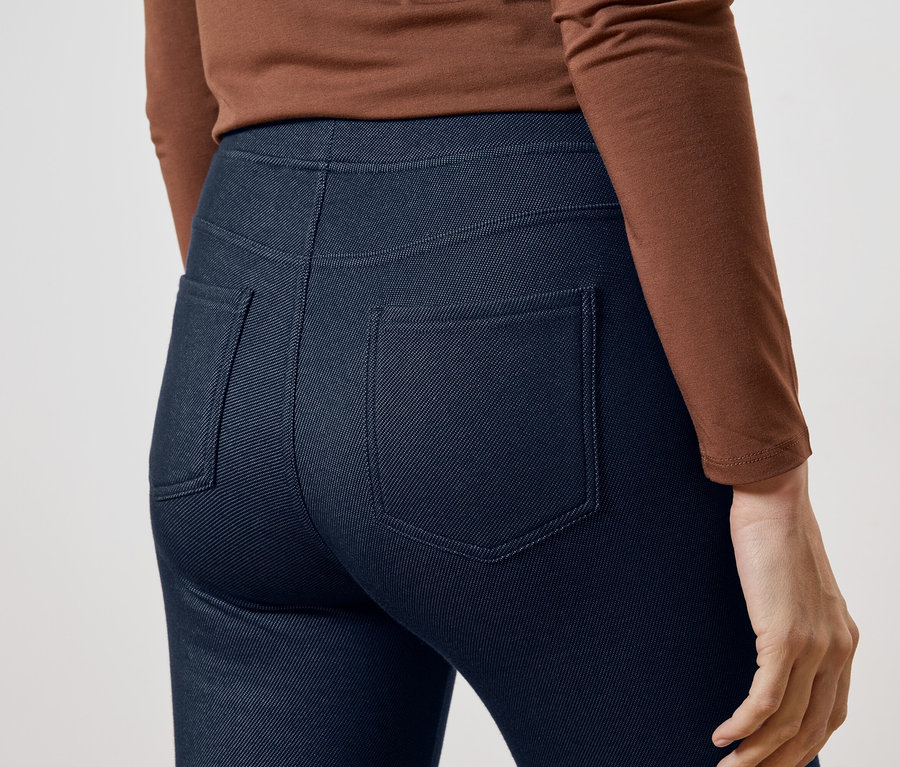Nahaufnahme der Rückansicht einer Frau mit braunem Oberteil und blauen Hosen mit Gesäßtaschen.