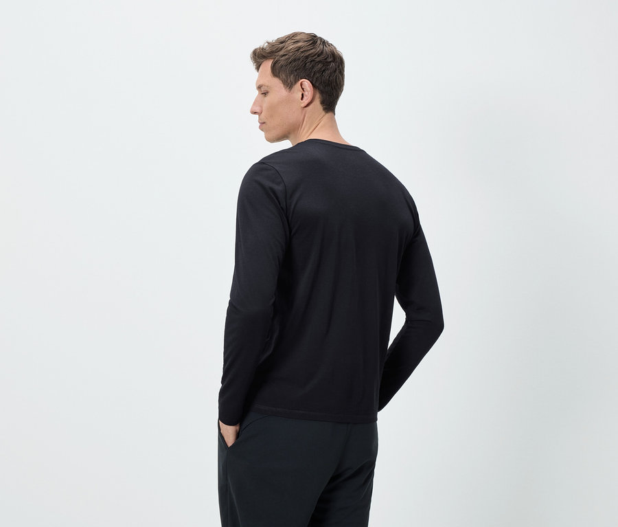 Mann von hinten in schwarzem langärmligem Shirt und Hose.