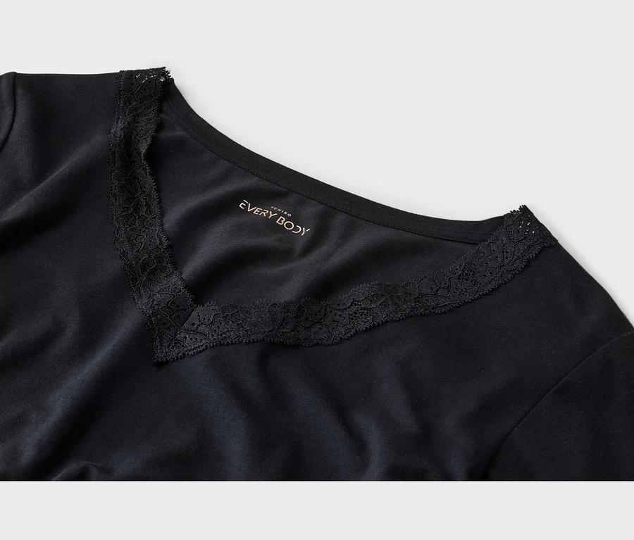 Nahaufnahme eines schwarzen T-Shirts mit V-Ausschnitt und Spitzenbesatz. Das "EVERY BODY"-Logo ist aufgedruckt.