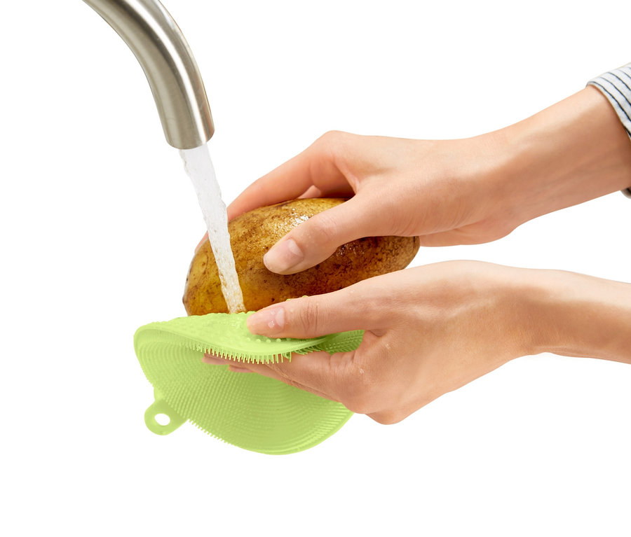 Frau wäscht eine Kartoffel unter fließendem Wasser mit einem 2 Silikon-Abwaschpads.
