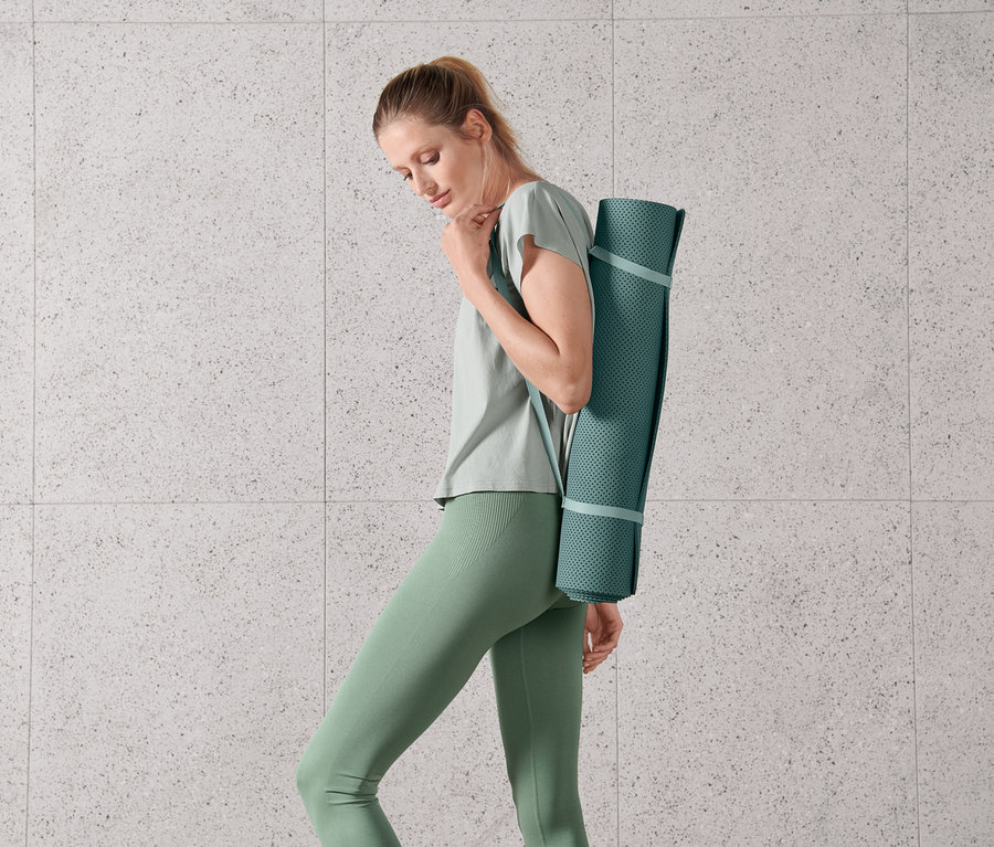 Frau trägt eine Yoga- und Fitnessmatte.