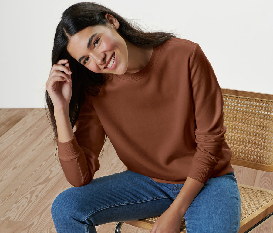 Frau sitzt auf einem Stuhl und trägt ein Sweatshirt.