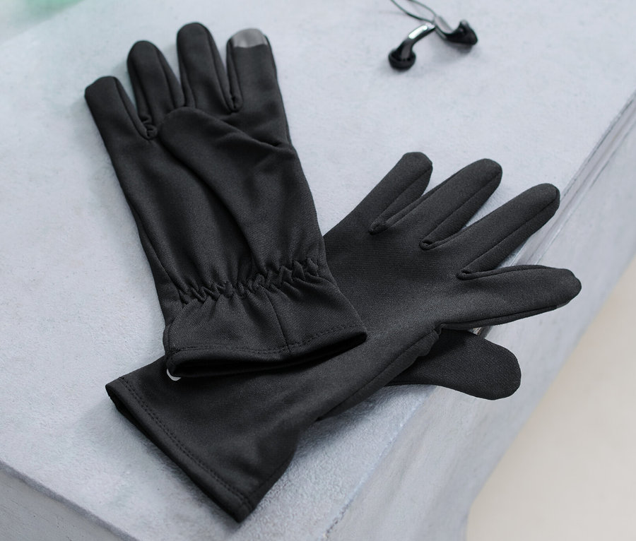 Laufhandschuhe, eine Wasserflasche und Kopfhörer liegen auf einer Bank.