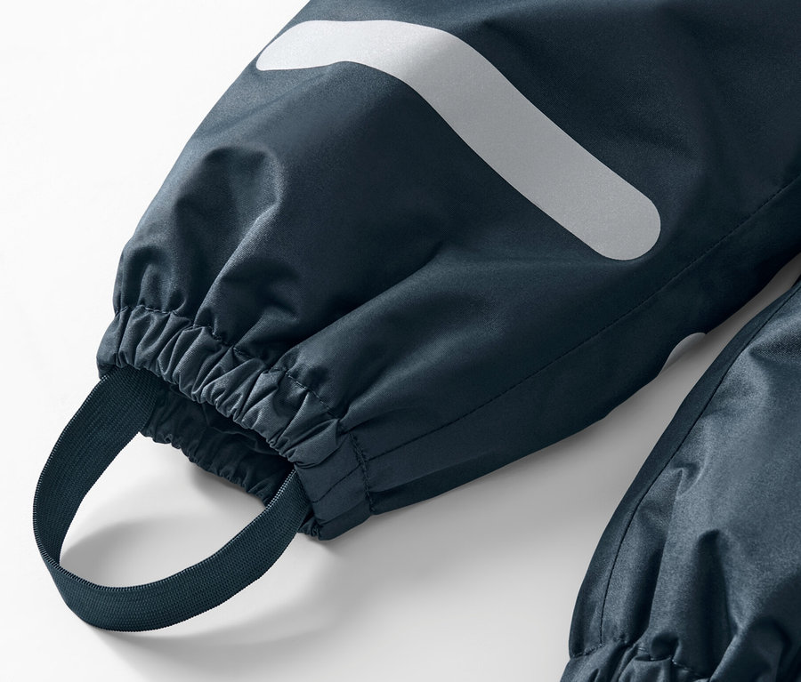 Detail einer Kinder-Regenhose mit Reflektor und Gummizug.