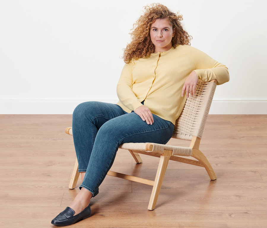 Frau sitzt im Sessel und trägt Treggings »Fit Nelly« und Feinstrick-Cardigan.