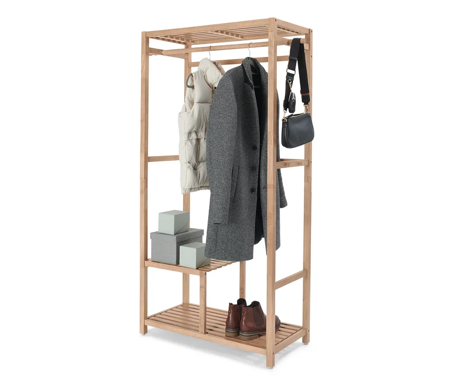 Kleidung hängt an einer Garderobe, Massivholz. Schuhe und Schachteln stehen im unteren Regal.