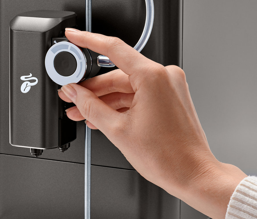 Eine Hand dreht am Milchschaumdrehregler für Tchibo Vollautomaten des »Esperto 2 Milk« Granite Black.