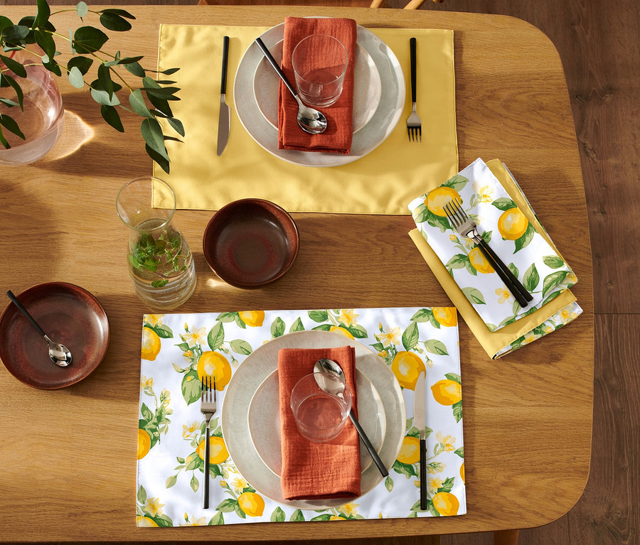 Zwei gedeckte Tische mit 4 Wende-Platzsets, Tellern, Besteck und Gläsern.