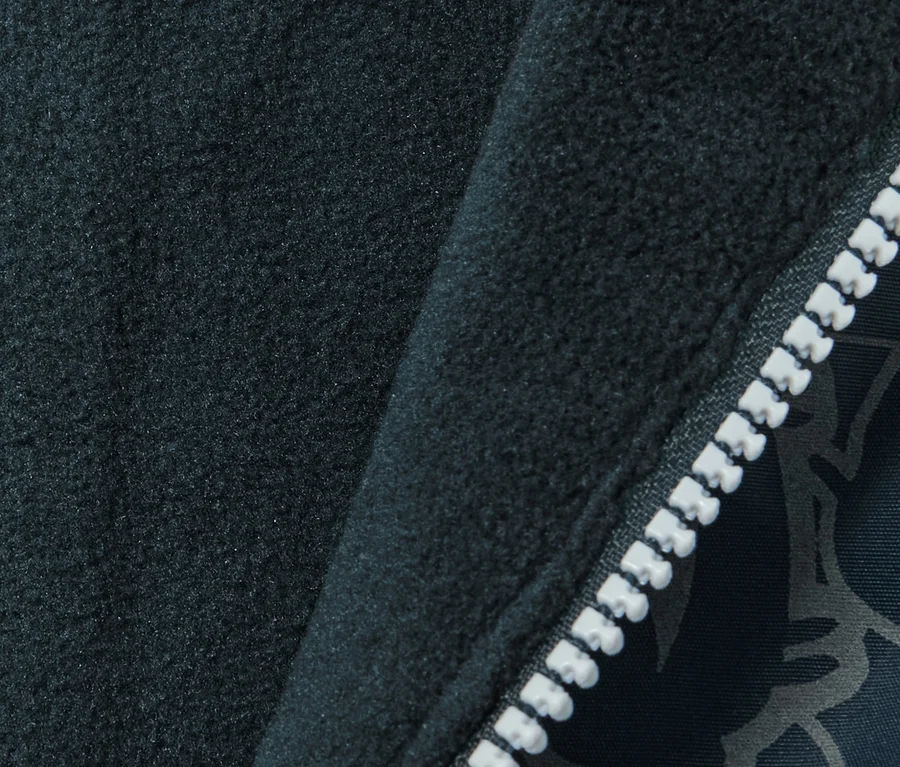 Detailaufnahme einer dunkelblauen Kinder Thermo-Regenhose mit reflektierenden Elementen und einem weißen Reißverschluss.