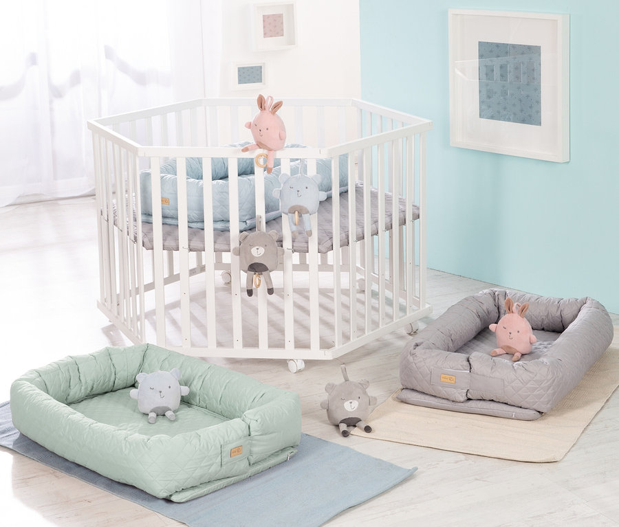 Weißes Kinderbett mit Spielzeug und zwei grüne und graue Babyschalen. Roba 3-in1-Babylounge, grün.