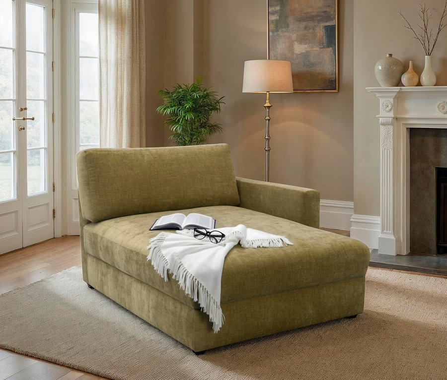 Grüne Chaiselongue mit Buch, Brille und weißer Decke im Wohnzimmer.