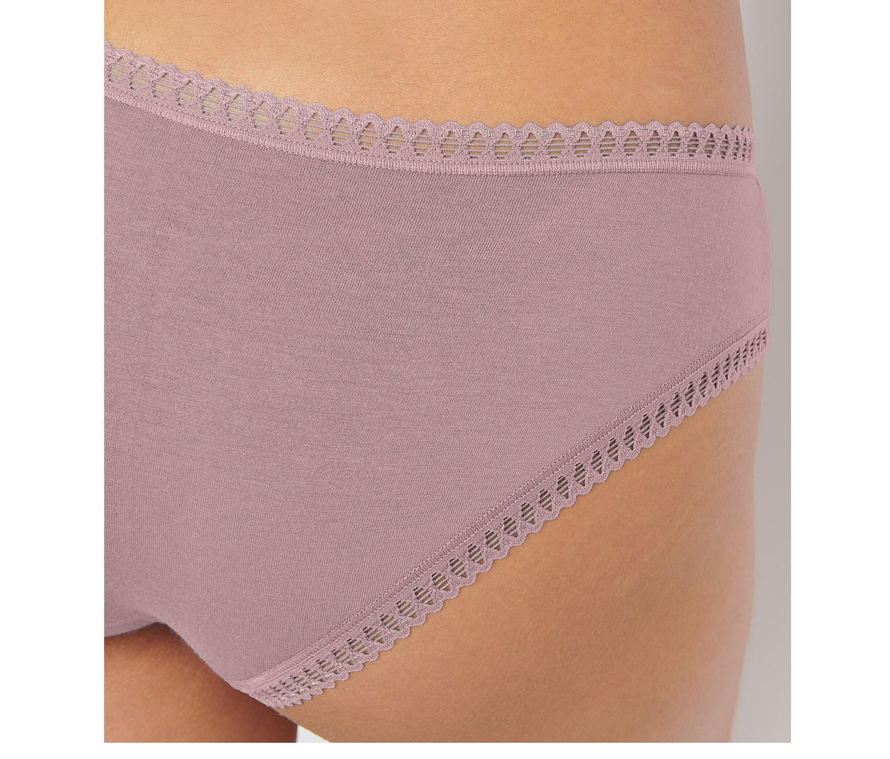 Nahaufnahme einer Person, die einen rosafarbenen sloggi GO Crush Hipster Slip mit gewellter Spitzenborte an Bund und Beinausschnitten trägt.