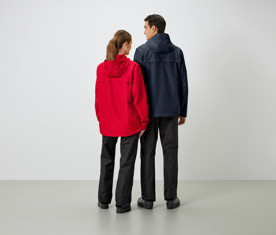 Zwei Personen stehen mit dem Rücken zur Kamera und tragen Regenjacken und Regenhosen.