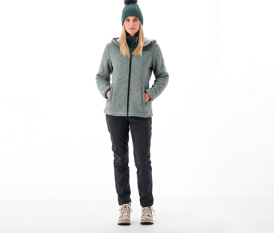 Frau steht und trägt CMP Damen-Softshellhose, Jacke und Mütze.