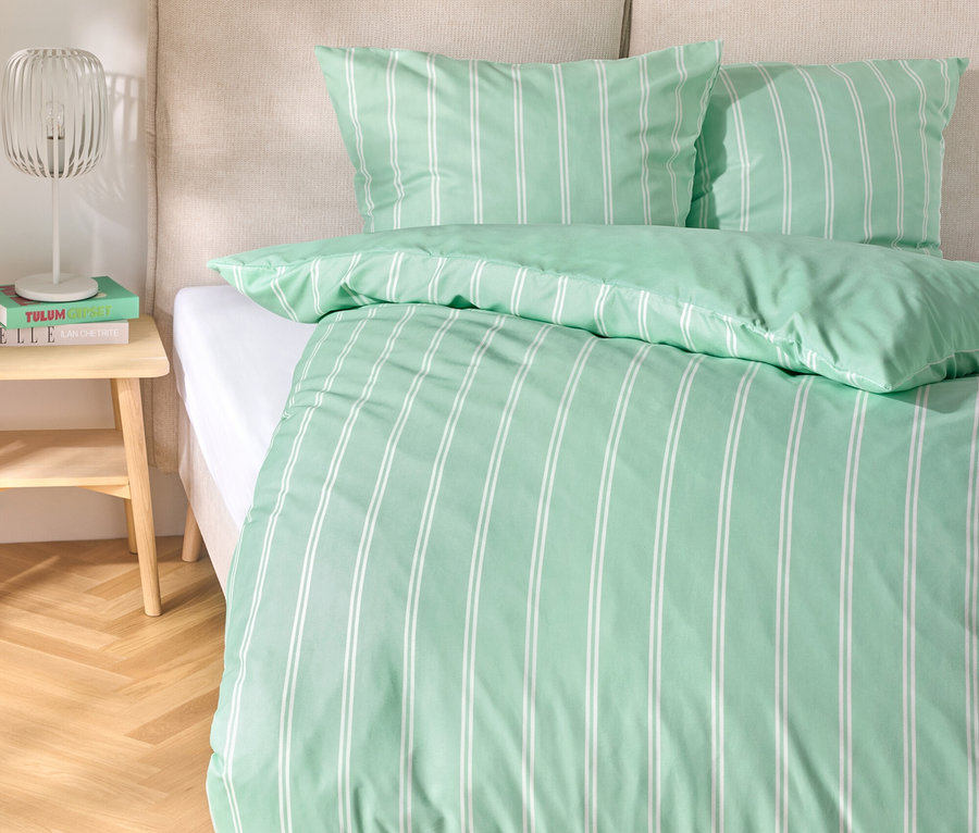 Bett mit hellgrüner Microfaser-Bettwäsche, Normalgröße und Übergröße, mit weißen Streifen.