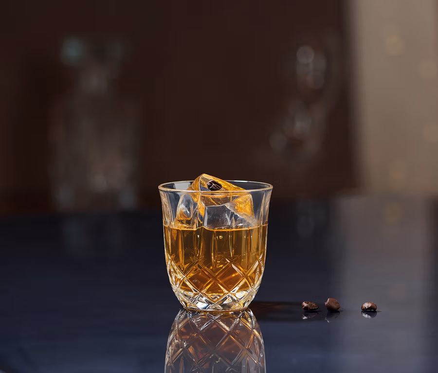 Ein Nachtmann Espressoglas »Noblesse« gefüllt mit einem Getränk und Eiswürfeln steht auf einer dunklen Oberfläche.