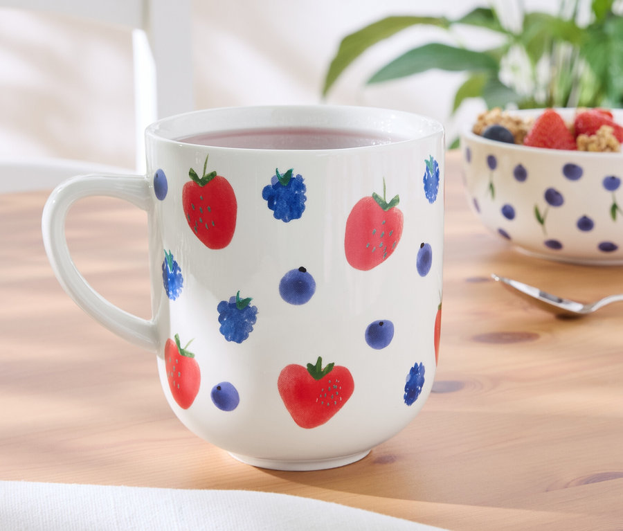 Auf einem Tisch steht ein Jumbobecher mit Erdbeer- und Blaubeerdesign.