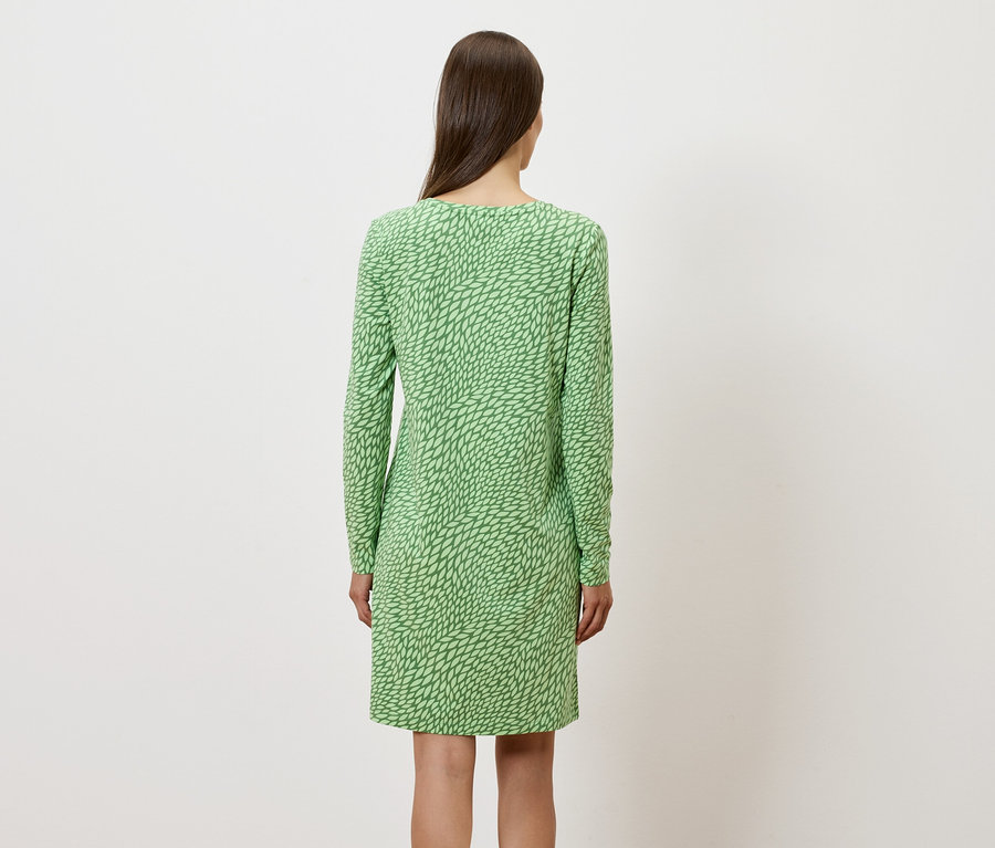 Rückansicht einer Frau in einem grünen, langärmeligen Kleid.