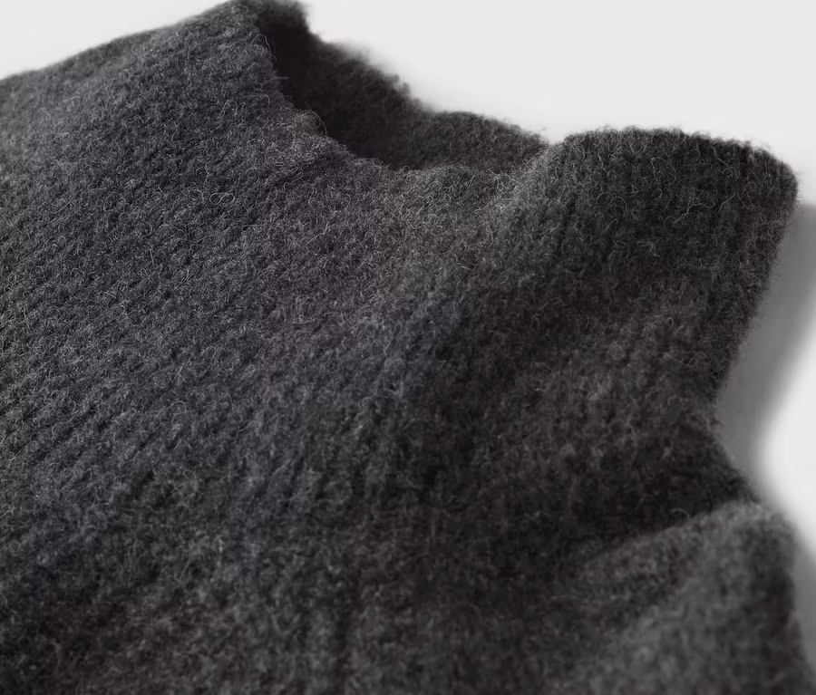 Detailaufnahme der Textur eines grauen Pullovers.