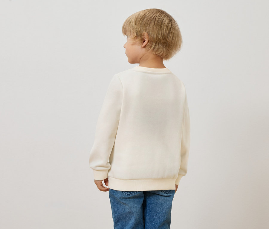 Rückansicht eines blonden Kindes mit einem Kinder-Sweatshirt mit angerauter Innenseite, Sonne und blauen Jeans.