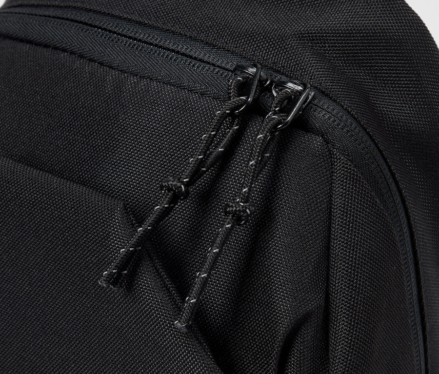 Nahaufnahme eines schwarzen Rucksacks mit Reißverschluss und Kordelzug.