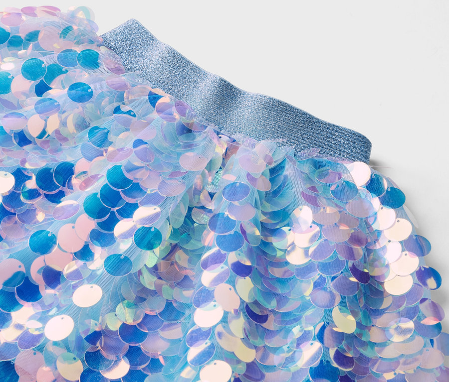 Nahaufnahme eines Tüllrocks mit blauen Pailletten und einem glitzernden, elastischen Bund.