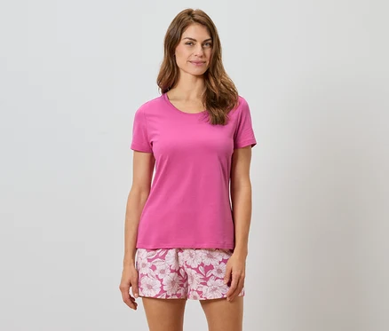Frau trägt ein pinkes T-Shirt und Shorts mit Blumenmuster.