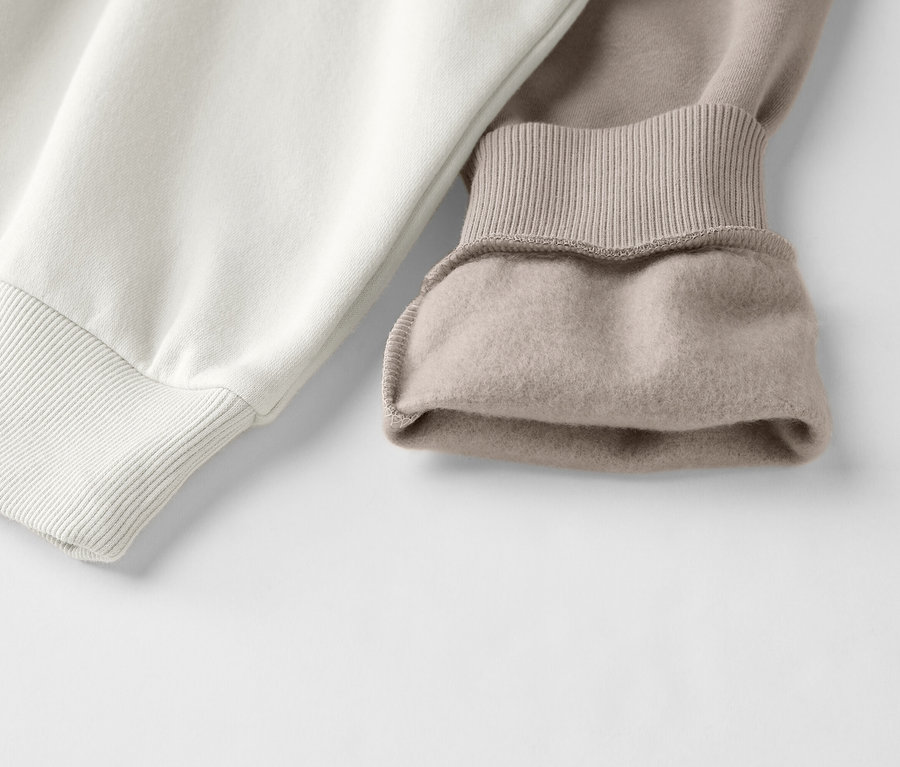 Nahaufnahme eines zweifarbigen Sweatshirts in Weiß und Beige mit gerippten Bündchen.