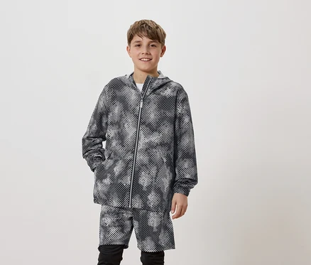 Ein junger Mann trägt eine Kapuzenjacke mit Punktmuster und passende Shorts.