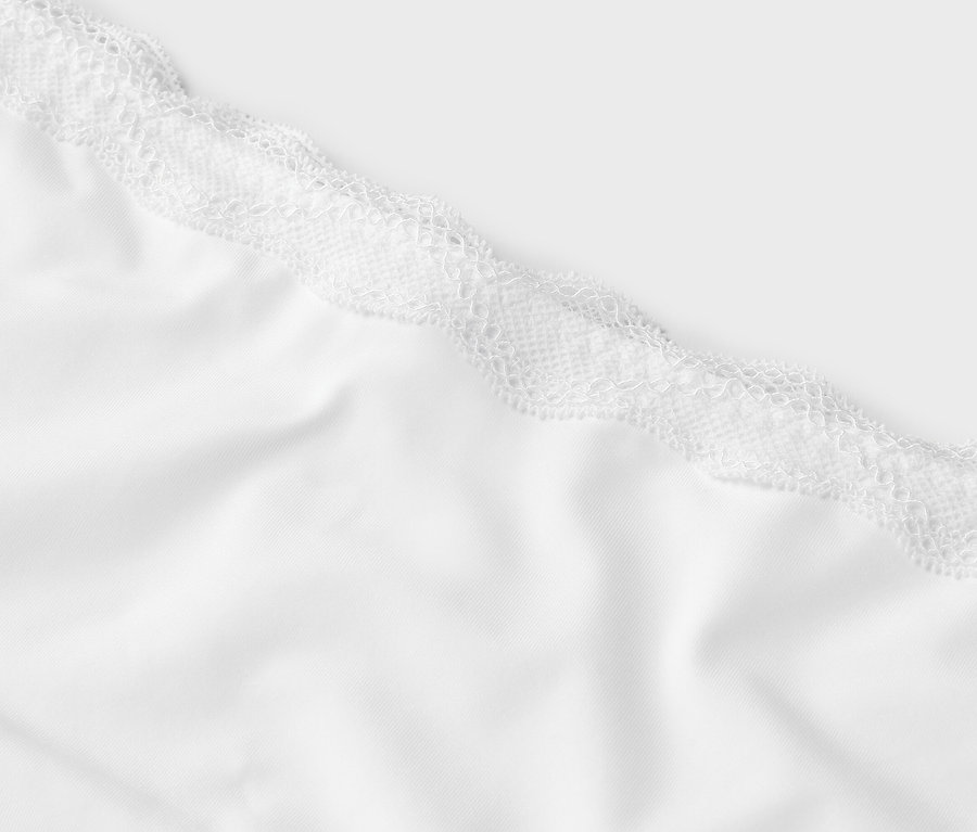 Detailansicht eines weißen Stoffes mit weißer Spitze an der Oberseite.