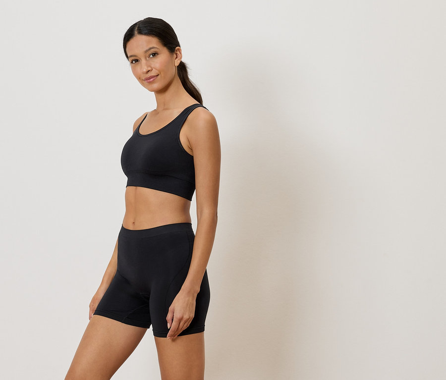 Frau trägt einen schwarzen Sport-BH und Shorts.