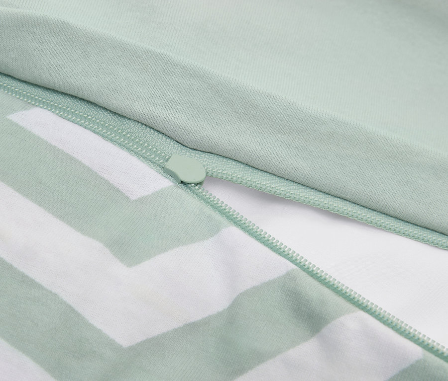 Nahaufnahme eines hellgrün gestreiften Kissenbezugs mit Reißverschluss.