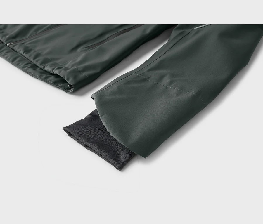 Nahaufnahme einer dunkelgrau-grünen Jacke, die den Hauptteil mit Reißverschluss und einen Ärmel mit dunklerem geripptem Innenbündchen zeigt.