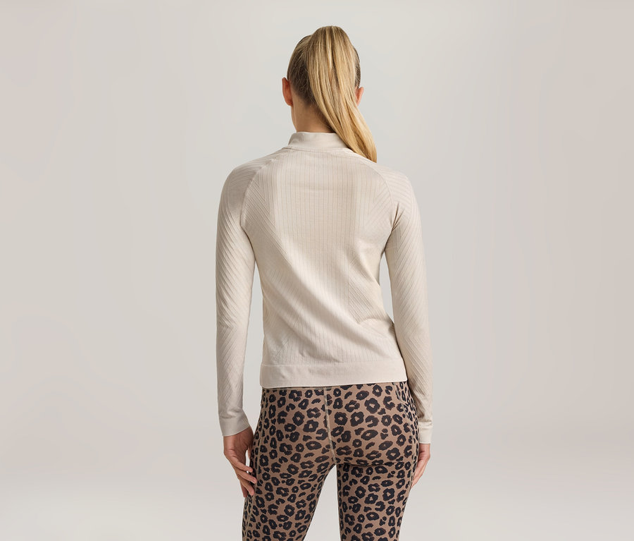Frau von hinten, trägt ein hellbeiges, geripptes Langarmshirt mit Stehkragen und Leggings mit Leopardenmuster.
