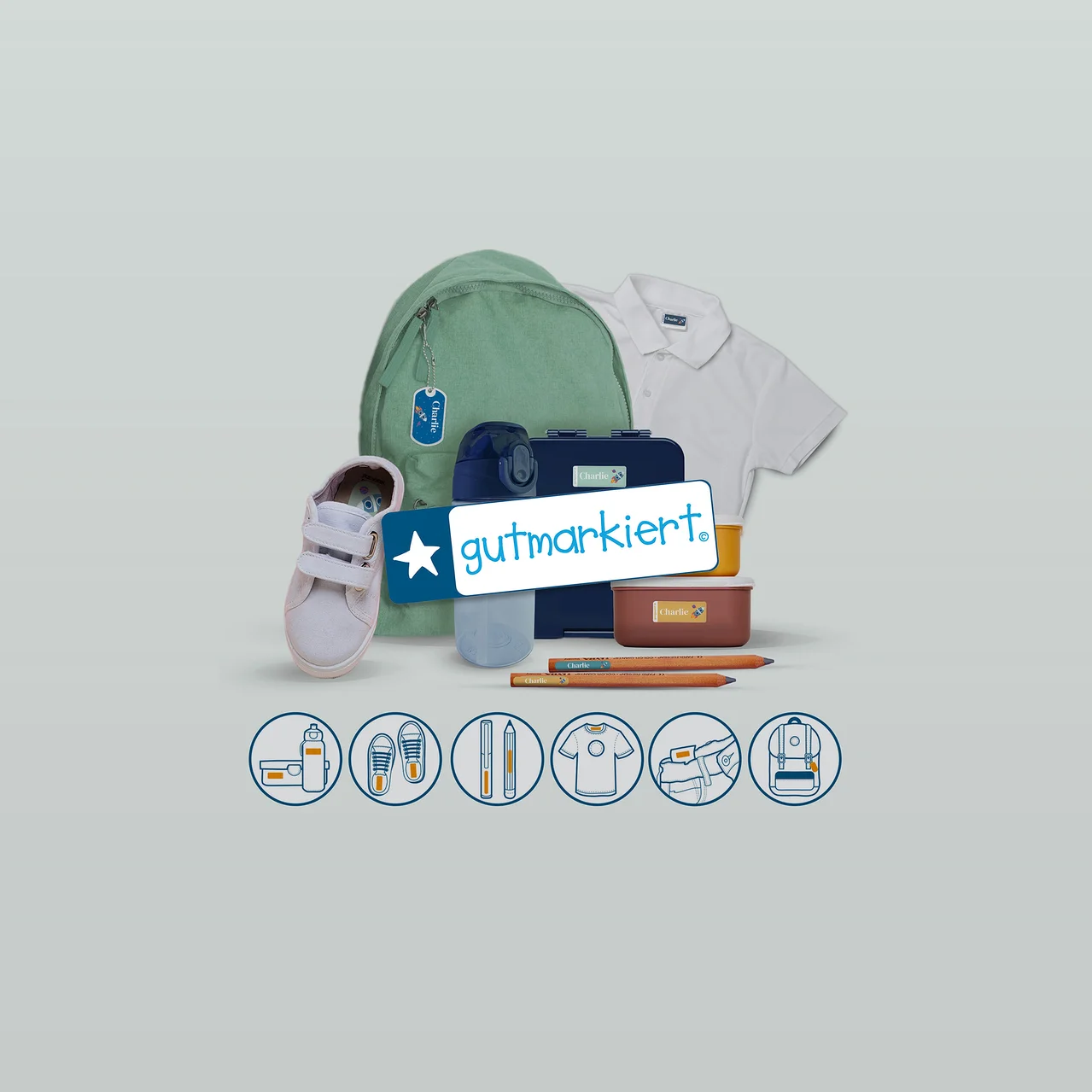 Grüner Rucksack, weißes Poloshirt, rosa Schuh, blaue Trinkflasche, blaue und braune Brotdosen, Bleistifte, viele mit "Charlie"-Etiketten, um das "gutmarkiert"-Logo angeordnet. Unten Symbole für Flaschen, Schuhe, Stifte, Hemden, Rucksäcke.