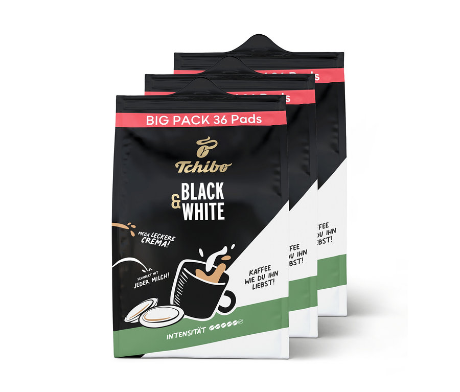 Drei Packungen Tchibo BLACK & WHITE Pads, die vorderste Packung zeigt den Namen und eine Tasse Kaffee mit Milchschaum.