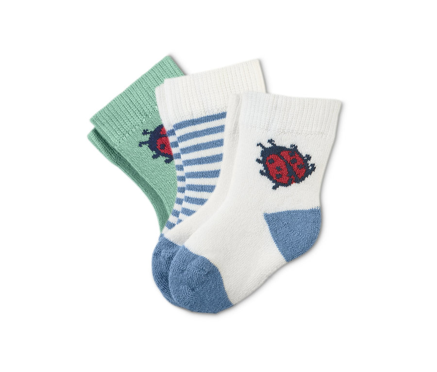 Nahaufnahme von drei Paar Frottier-Babysocken: ein Paar hellgrün mit Marienkäfer, ein Paar weiß mit blauen Streifen und ein Paar weiß mit Marienkäfer und blauer Ferse.
