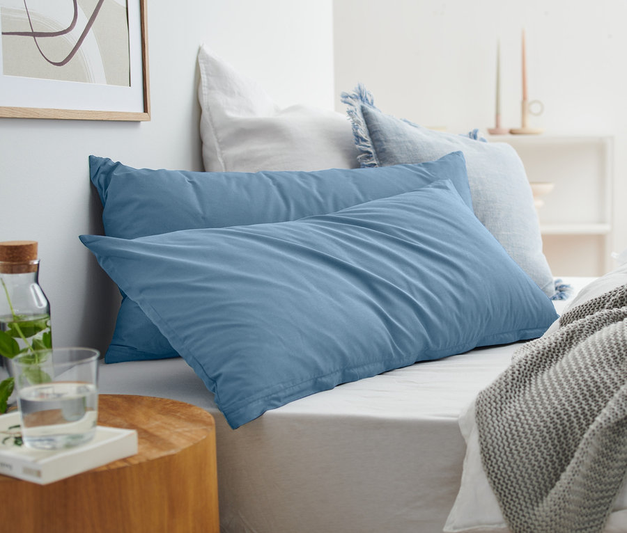 Auf einem Bett liegen zwei blaue Renforcé-Kopfkissenbezüge.